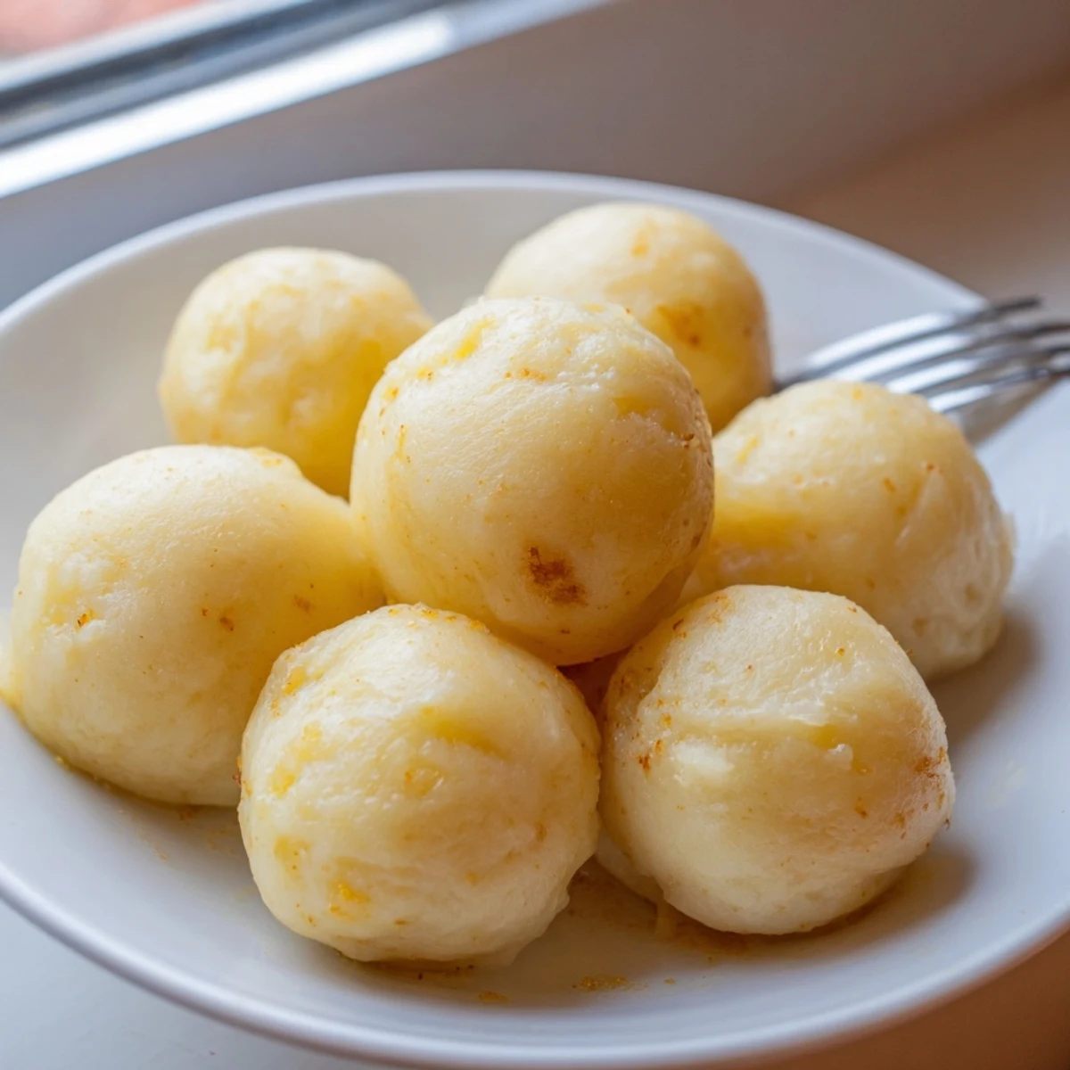 Pillowy Kartoffelknödel serviert mit sämiger Bratensoße und frischen Kräutern.  