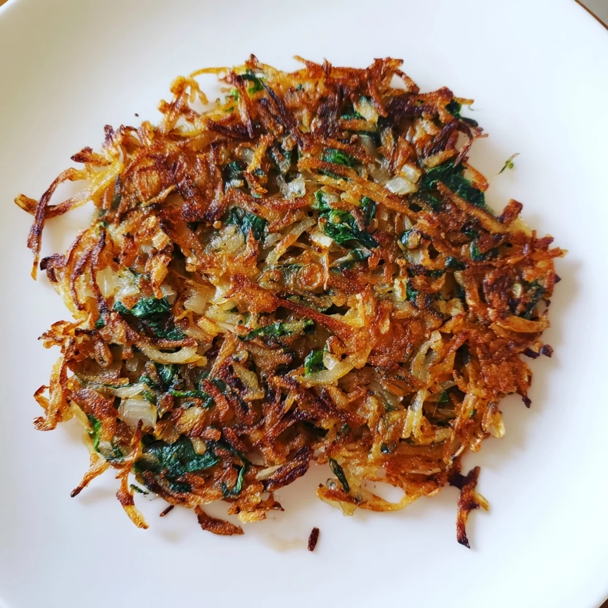Crispy potato and spinach rösti, a golden brown, Swiss-inspired dish ready to serve.