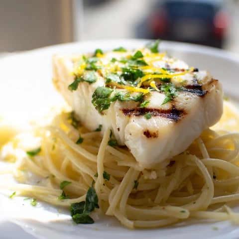 Grilled Lemon Bass Pasta mit frischen Kräutern und Parmesan auf einem weißen Teller angerichtet.