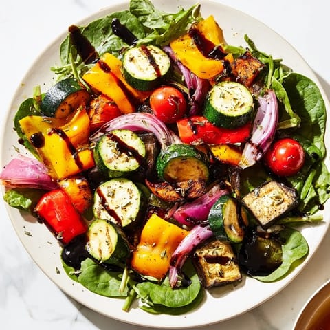 A close-up of a flavorful Roasted Vegetable Salad, drizzled with balsamic dressing and ready to serve.