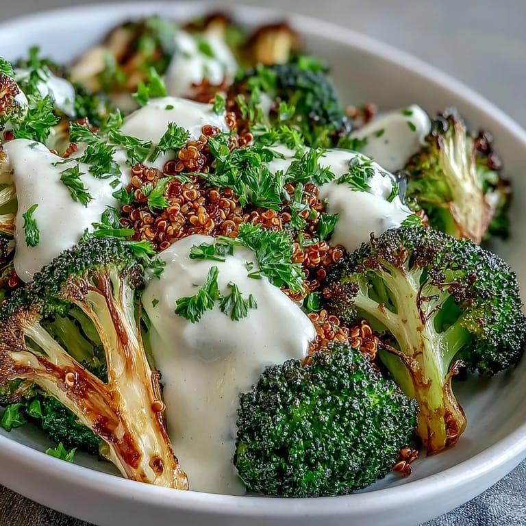 Golden roasted broccoli bowl drizzled with tahini sauce, topped with fresh parsley.